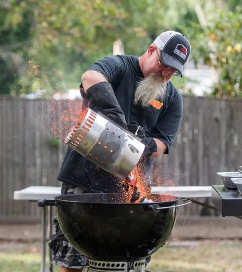 Man adding charcoal to a grill outdoors