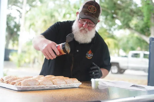 Man with a beard and cap preparing food outdoors