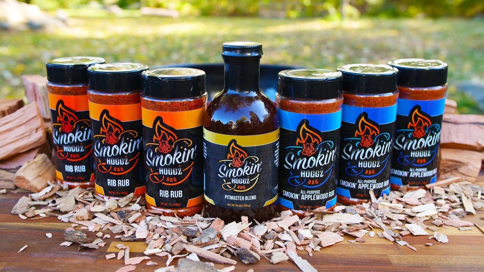Collection of 'Smokin' Hoggz' barbecue products on a wooden surface with a blurred natural background.